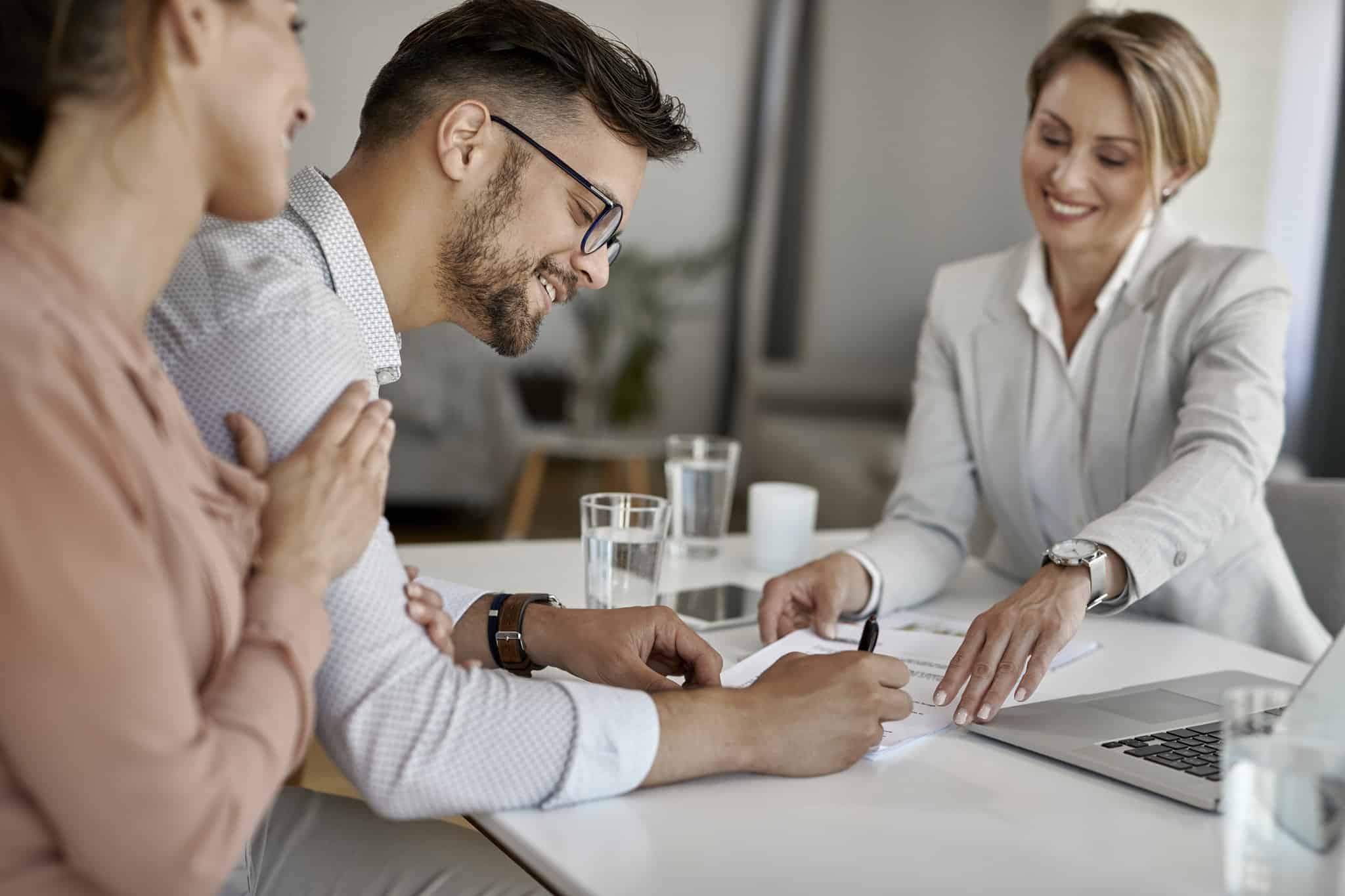 Happy man and his wife having a meeting with financial advisor and signing an agreement in the office.